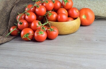 Fototapeta na wymiar Small garden Cherrys tomatoes on the branch on wooden table, space for text