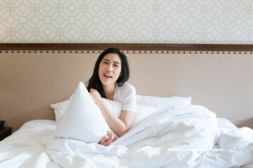 Attractive young beautiful girl stretching in the bed at home. Pretty young girl in white on bed in...