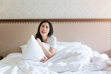 Attractive young beautiful girl stretching in the bed at home. Pretty young girl in white on bed in...