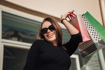 Portrait of european lady hold hand colorful bags woman after shopping in black dress sunglasses on...