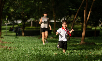 Fototapeta premium Cute boy running across grass and smiling.