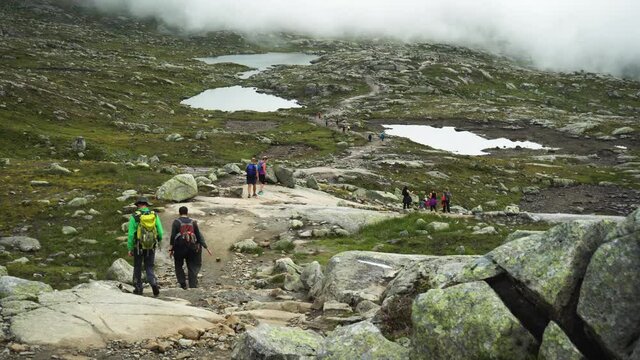 Tourists coming down the hill of the mountain in Odda Telemark on the path of Trolltunga in Norway.