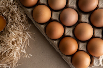 Close-up view of brown chicken eggs in carton egg crate on neutral background.