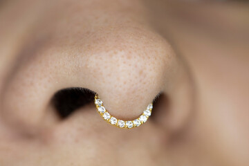 Nose piercing septum. Beautiful piercing jewelry. Macro shot. Selective focus.