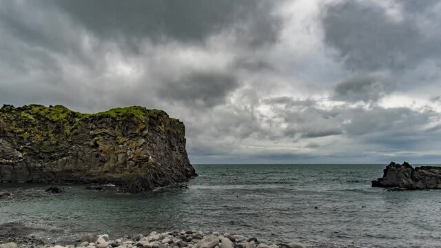 Clouds moving over the ocean behind the rocky features of Hellnar Iceland.