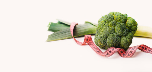 green leek, broccoli and tape measure on the white background