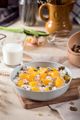 Homemade cottage cheese with apricots and nuts in a bowl on old wooden table