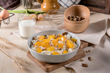 Homemade cottage cheese with apricots and nuts in a bowl on old wooden table
