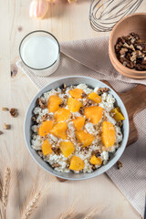 Homemade cottage cheese with apricots and nuts in a bowl on old wooden table