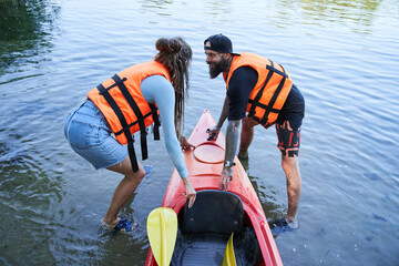 Man and girl in safe jacket pulling canoe