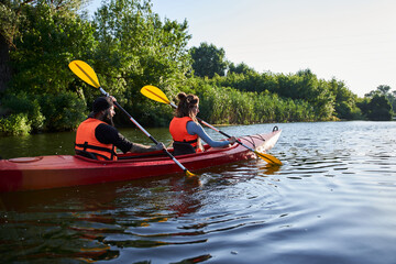 Couple kayaking on river at evening