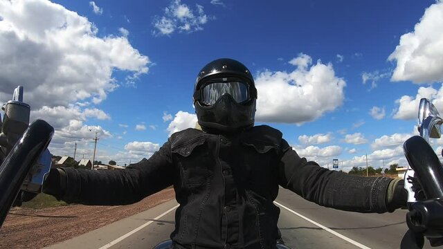 Male Motorcyclist, In Black Denim Jacket And Helmet With Sun Mask, View From Camera On Handlebars Of Motorcycle. Tough Guy On Motorcycle Rides In Highway, Third Person View