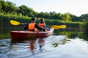 Fototapeta premium Couple kayaking on river at evening