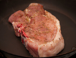 Fresh raw pork steak with spices roasting on frying pan