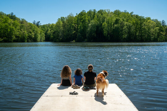 Family And Dog On The Edge Of A Dock On A Lake