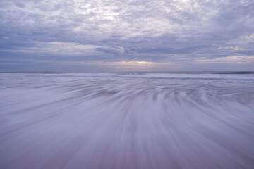 Long speed shutter of tropical sandy beach with sky and clouds over sea.