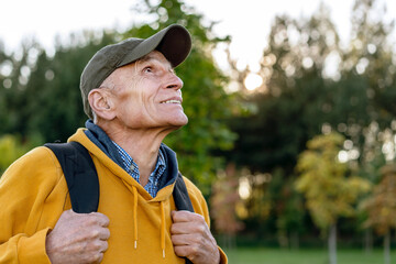 Obraz premium wisdom senior hiker man with packback looking on top of high mountain autumn forest background