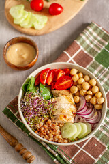 
Healthy salad bowl with buckwheat, tomatoes, chicken, onion ,cucumber, chickpeas and mixed greens on a table. Top view. Food and health.