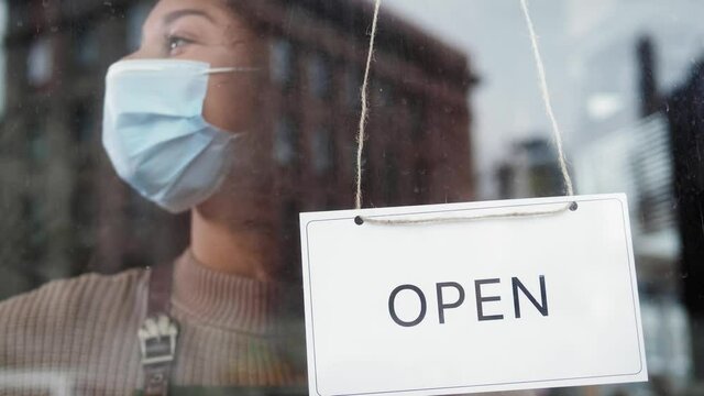 cafe or restaurants and business reopen after coronavirus quarantine is over. woman with face mask turning a sign on a door shop. small business after covid lockdown. business open sign.