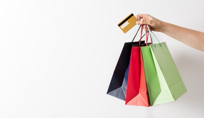 Woman hand holding group of colorful paper shopping bags and credit card over white background.