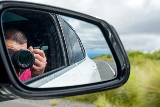 Road trip taking a photo reflected in side view mirror
