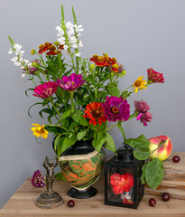 Still life with a bouquet of flowers, a lantern with a rose flower inside, an antique bronze figurine and a ripe apple. Vintage. Retro.