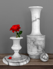 Red rose in a white marble vase. Large pitcher and balls in marble. Still life.