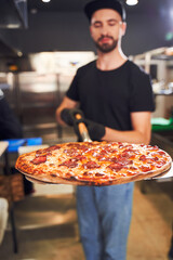 Pizzaiolo holding pizza on peel