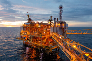 Offshore oil and gas rig platform with beautiful sky in sunset time for business industry concept.