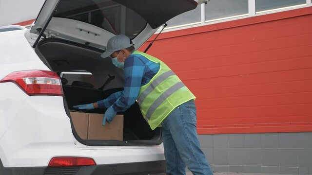 Volunteer wearing a mask and gloves delivers parcels. Online shopping during the covid-19 coronavirus pandemic. Contactless delivery of goods by courier service. Delivery during the coronavirus period
