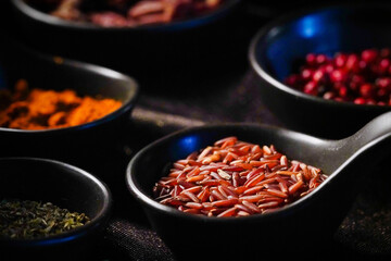 Brown/Red rice seeds in a spoon With various spices In low light conditions, rice is ready to be cooked.