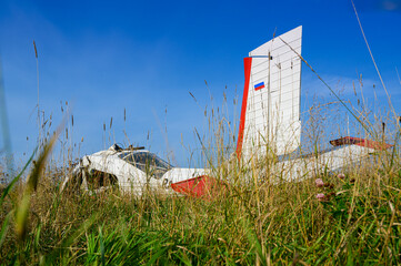 a broken abandoned airplane after a disaster on a green grass of a countryside airdrome