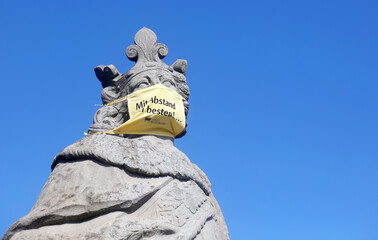 Statue auf der alten Mainbrücke in Würzburg mit Mundschutz während der Corona Pandemie