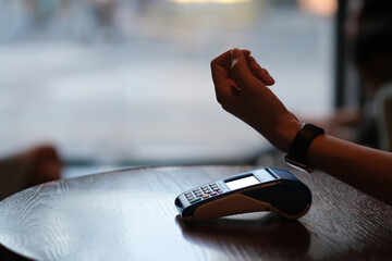 close up hand using smart watch pay over POS terminal in bar counter