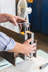 worker in a factory holds squeezes two metal beams by the vice