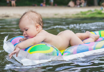 beautiful baby floating on air mattress on the river