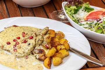 Pork Cutlet with wine - cream - herbs - sauce with fried potatoes and mixed salad