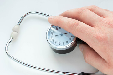 sphygmomanometer and stethoscope in doctor's hand on white background. Close-up
