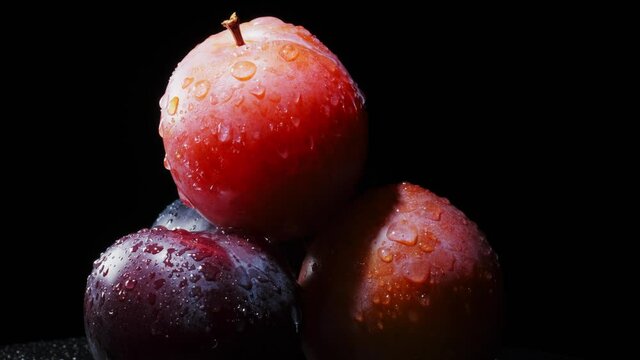 ripe red and purple plum fruits isolated on black background