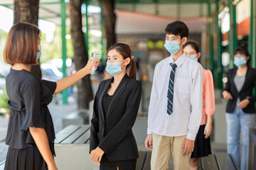 Office workers standing in line must go through fever measures using infrared digital thermometer check temperature measurement on the forehead during the coronavirus pandemic. Covid-19.