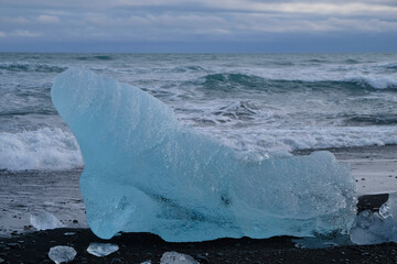 Iceberg looking like a manatee or a walrus stranded on Jökulsarlon diamond beach in winter on...