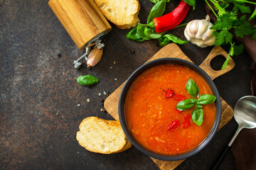 Vegan healthy food. Tomato soup or gazpacho on a dark stone or slate table. Flat lay top view. Copy space.