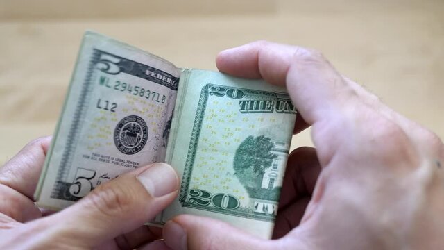 Tri folding US cash, including a five dollar and 20 dollar bill