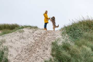 Junge blonde Frau auf einem Hundespaziergang durch die Dünen