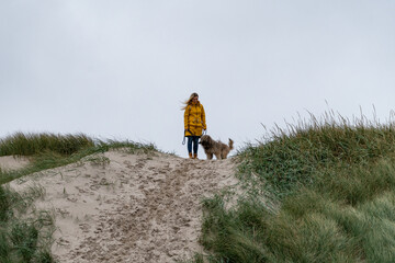 Junge blonde Frau auf einem Hundespaziergang durch die Dünen