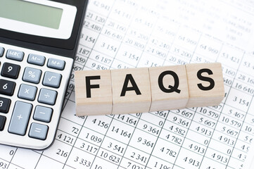 concept of FAQS word on wooden cubes lying on white background with calculator
