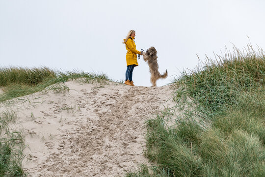 Junge blonde Frau auf einem Hundespaziergang durch die D&uuml;nen