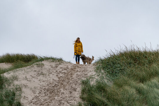 Junge blonde Frau auf einem Hundespaziergang durch die D&uuml;nen