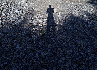 shadow of a person reflected on the ground of a stone beach