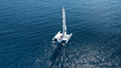 Aerial drone top down photo of small Catamaran sailboat sailing in Mediterranean popular Aegean destination with deep blue sea